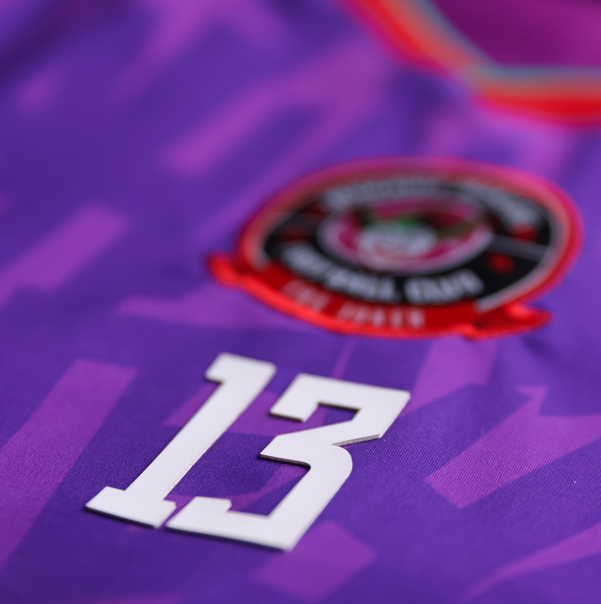 Close-up of the GOAT SKINS Joker limited edition collectible jersey showing the embroidered crest, number 13 and purple fabric detail